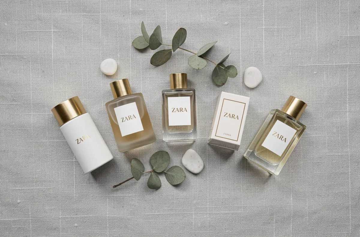 Vue de dessus de cinq flacons de parfums Zara femme disposés en arc sur tissu lin gris avec accessoires naturels